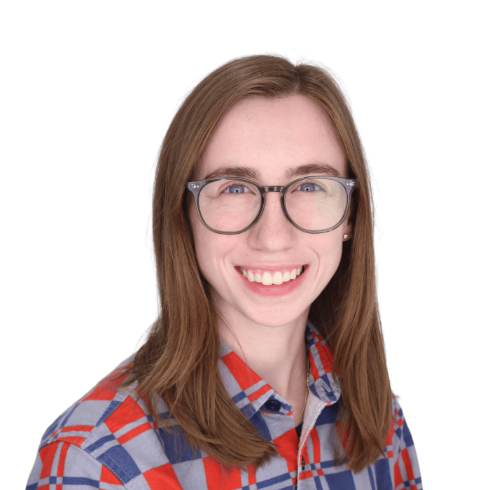 young woman with light brown hair, glasses, and a colorful shirt