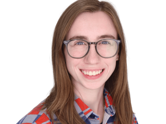 young woman with light brown hair, glasses, and a colorful shirt