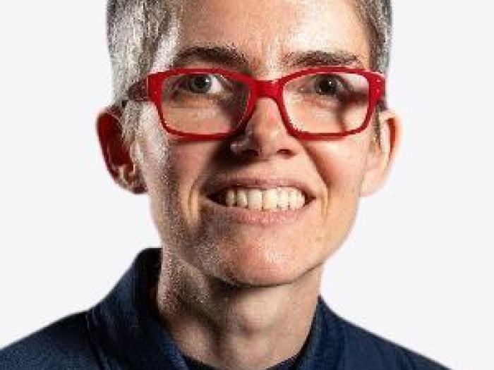Middle aged white woman with dark grey hair, a blue polo